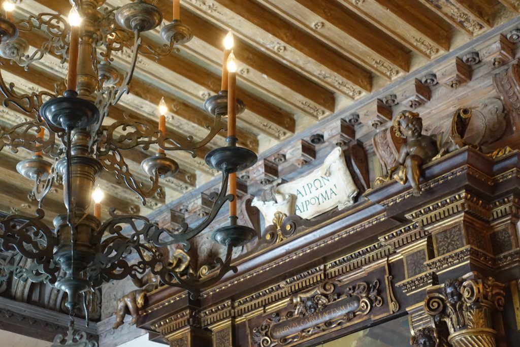 The visceral warmth and breathtaking detail of a wooden beam ceiling, chandelier and intricate carvings.