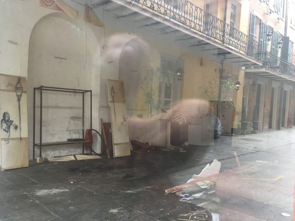 Empty storefront reflects the French Quarter outside - some places still feel ghost-town-y